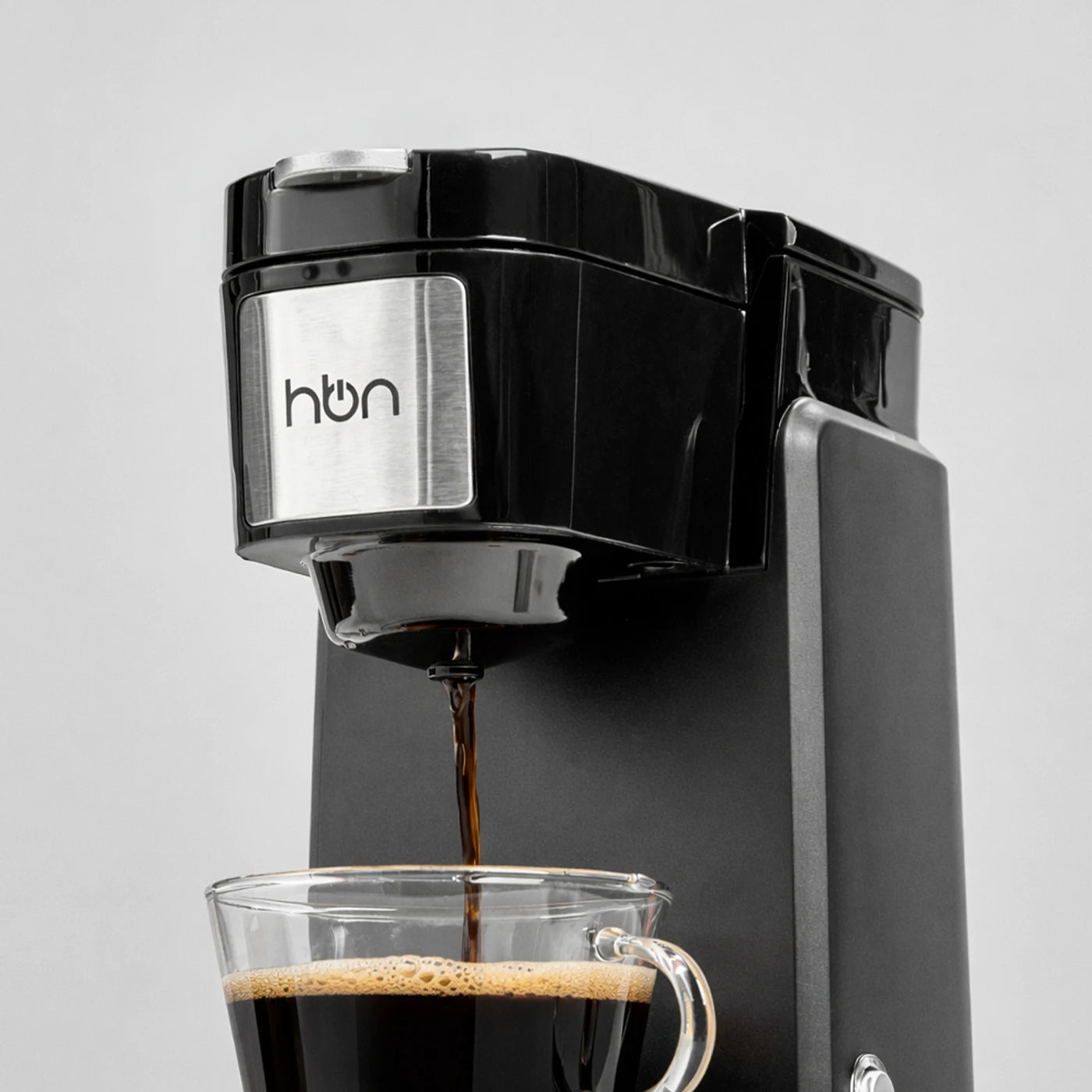 single serve coffee maker brewing coffee into glass cup close up