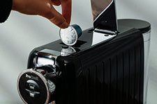 hand placing capsule into coffee machine for quick and easy home brewing